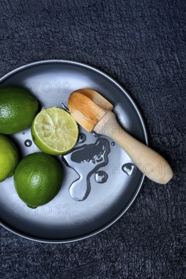 Limes with citrus squeezer on plate, halved