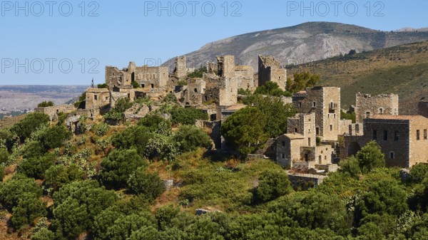 Historic stone buildings of a mountain village surrounded by trees and vast landscape, Vathia,