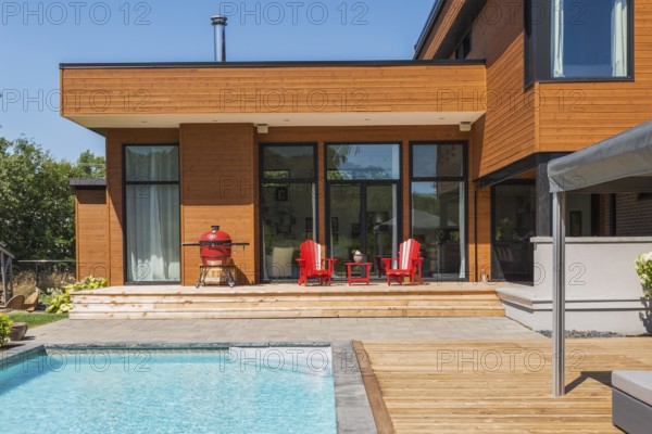 Rear of modern cube style home with stained horizontal wood cladding, in-ground swimming pool and