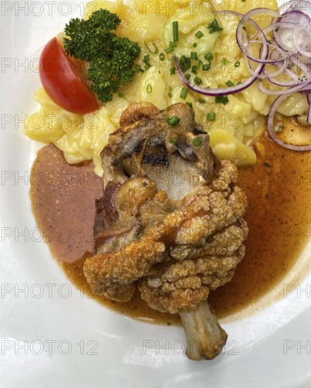 Half pork knuckle, crispy fried, potato salad, tomato, chives, parsley, onion rings, plate, food,