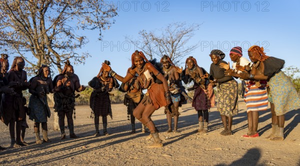 Group of traditional Himba woman standing in a semi-circle, clapping and dancing, music and dance,