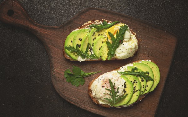 Sandwich with cream cheese, sliced avocado and boiled egg, arugula, on grainy bread, homemade,