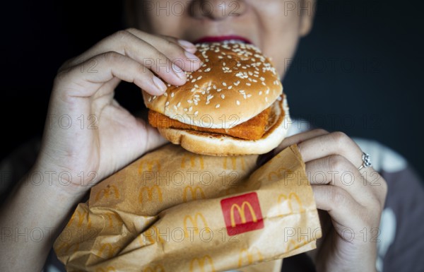 A woman eats a McDonald's burger on October 26, 2024 in Guwahati, India. McDonald's recent food