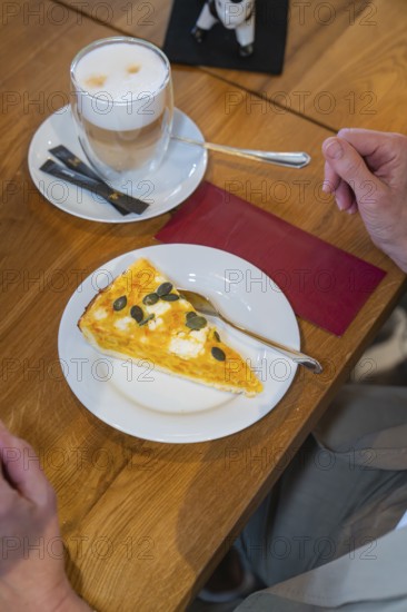 A slice of pumpkin pie on a plate and a cup of latte macchiato on a wooden table, autumn creations