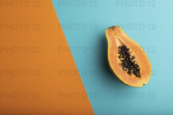 Ripe cut papaya on orange and blue pastel background. Top view, flat lay, copy space. Tropical,