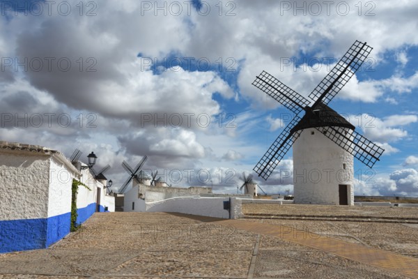 White windmills with blue stripes on old cobbled streets under a cloudy sky, Molino Sardinero,