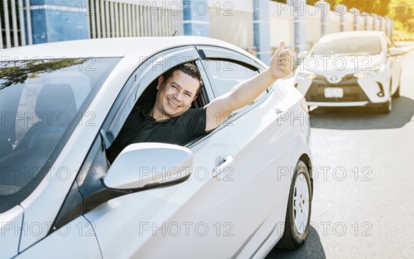 Smiling driver giving a thumbs up on the road. Satisfied driver man showing thumb up, safe driving