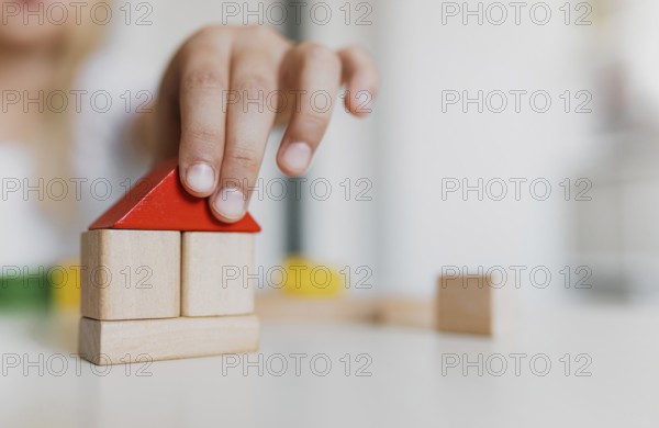 Little child girl of preschooler age playing wooden building blocks at home or kindergarten. Kid is