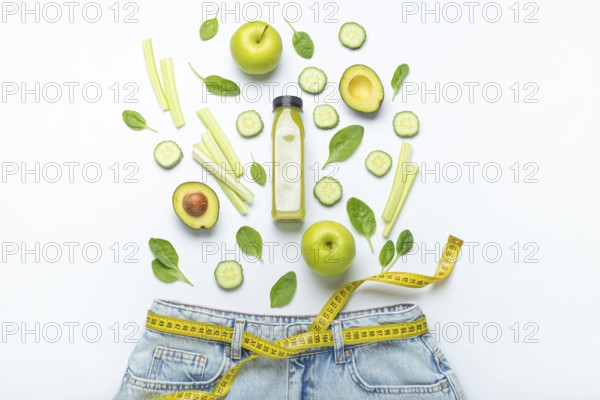 Green fruit, vegetables, smoothie falling into jeans and yellow measuring tape instead of belt on