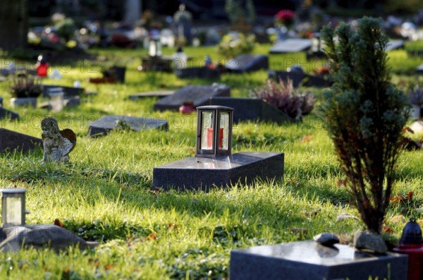 Lantern on a gravestone in a cemetery with graves of the poor against a blurred background