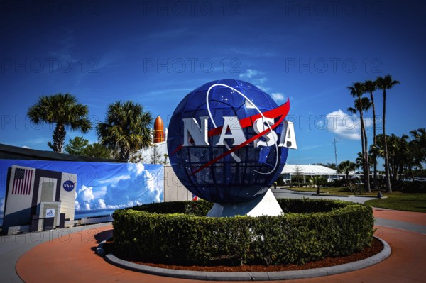 NASA logo with globe in front of blue sky and palm trees at the Kennedy Space Center, Cape
