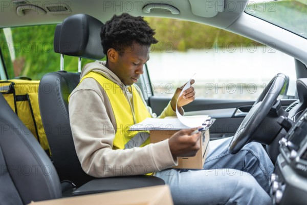 African delivery man, courier or logistics worker signing for a parcel writing on a checklist