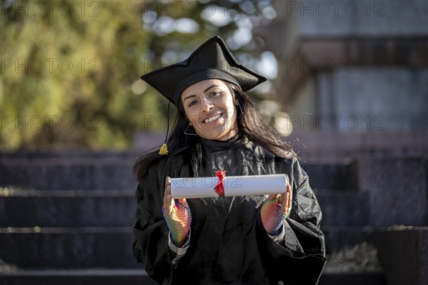 Transgender woman recent graduated, dressed in cap and gown, showing off his degree celebrating
