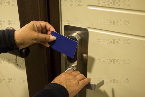 Hands holding a keycard near a door lock for entry, key electronic lock, hotel room, holidays in