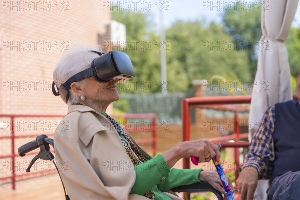 An elderly woman with the nurse looking through virtual reality glasses in the garden of a nursing