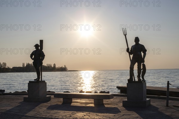 Sunrise on the shore and harbour of a lake in summer. Colourful sky with a wide view of the horiont