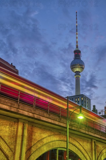The famous TV tower in Berlin at dusk with a motion blurred local train