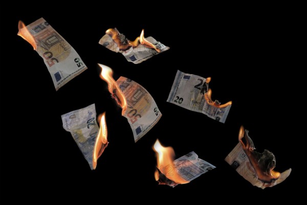 Burning money, twenty and fifty euro banknotes with flames flying isolated against a black