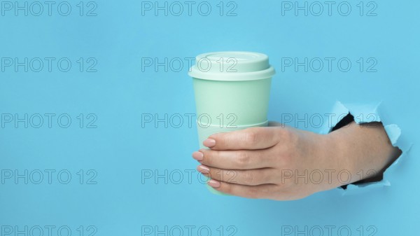 Front view hand holding reusable cup with copy space