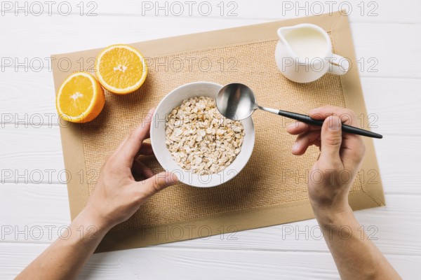 Person having oatmeal halved orange milk jute placemat white surface. High resolution photo
