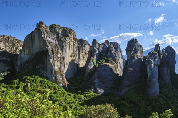 Midday view of Meteora rocks, sedimentary cliffs among bright spring greenery of valley. Sunshine,
