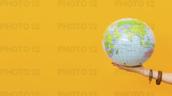 Side view hand holding globe with copy space