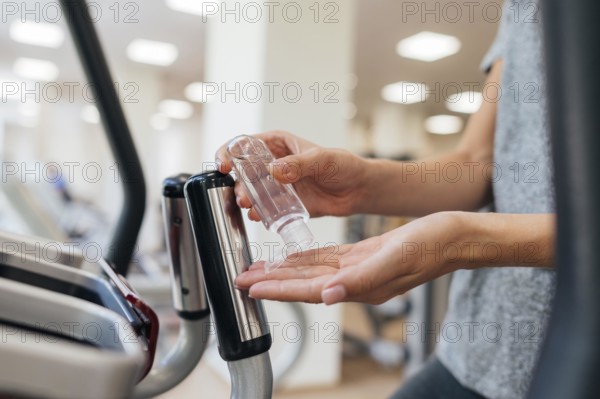 Side view woman using hand sanitizer gym during pandemic