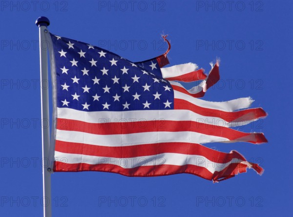 Stars and stripes, US national flag, torn, ripped, tattered, flutters flaps in the wind