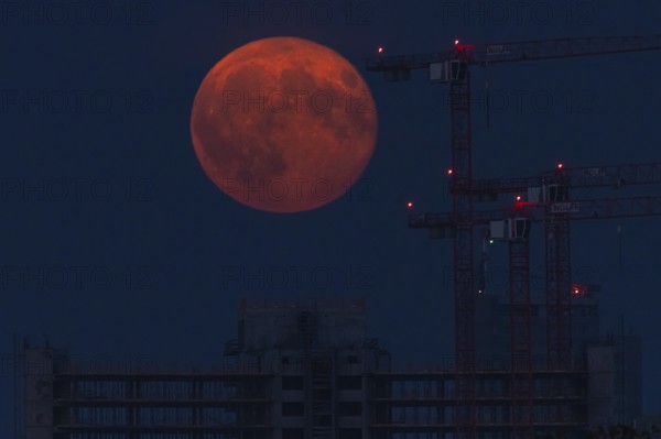 The full moon passes over a construction site in Offenbach am Main. A super moon will shine from