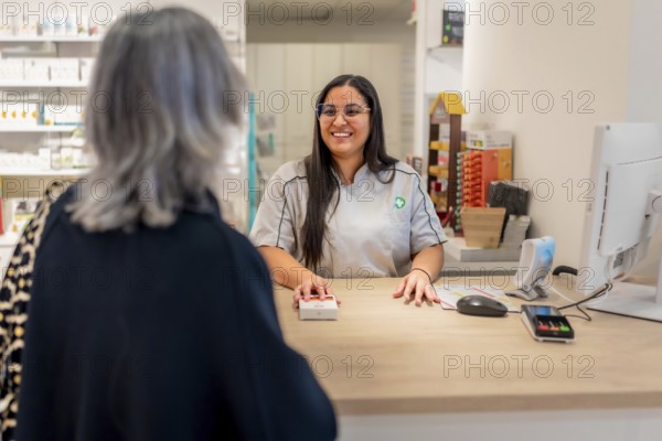 Friendly pharmacist talking to a mature female customer in the counter
