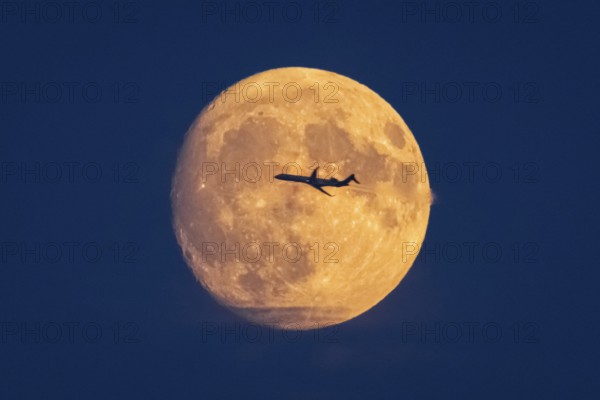 An aeroplane flies past in front of the yellow-orange full moon, Frankfurt am Main, Hesse, Germany,