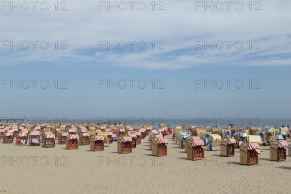 Symbolic picture weather, summer, bathers and beach chairs in front of a blue sky on the sandy