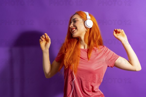 Redhead woman in studio photography dancing on a purple background, with a hard light