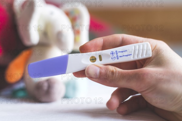 Woman hand holding pregnancy test, result is pregnant