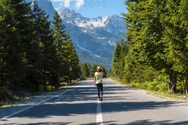 A woman walking on the road in the Valbona Valley, Theth National Park, Albanian Alps, Valbona