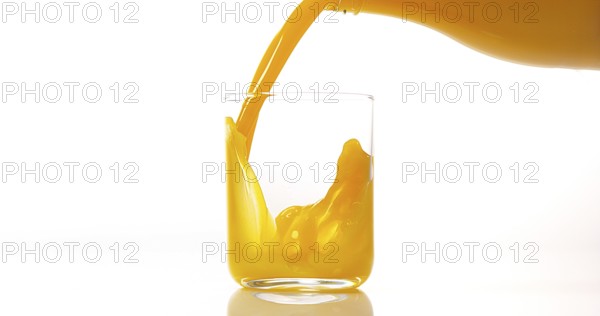 Orange Juice being poured into Glass against White Background