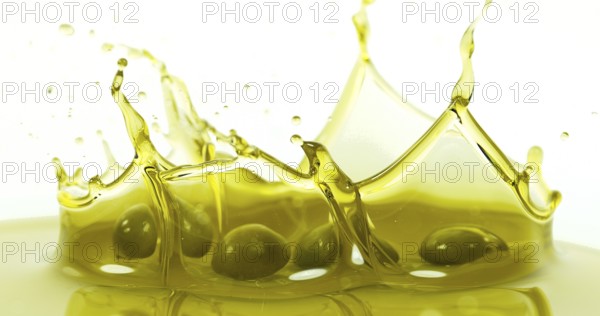 Olives Falling into Olive Oil against White Background