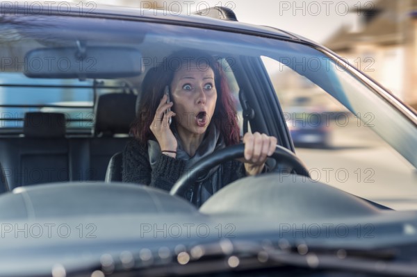 Young woman driving without a seatbelt and talking on her smartphone