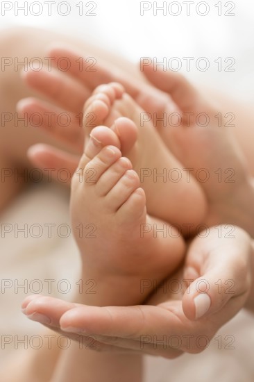 Close up mom holding baby s feet hands