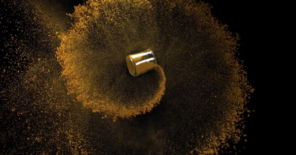 Curry Powder into a Small Jar falling against Black Background