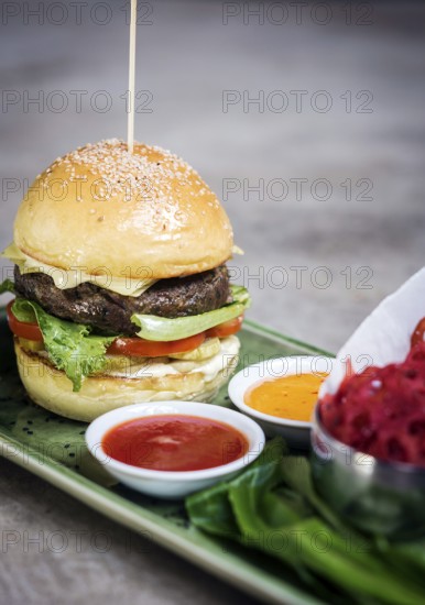 Modern fusion beef burger set with lotus chips ketchup and spicy chlli sauces