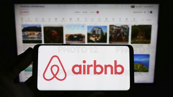 Stuttgart, Germany, 11-30-2022: Person holding smartphone with logo of US homestay marketplace