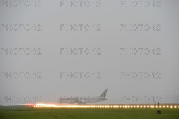 Overview Munich Airport with Qatar Airways, Boeing B787 Dreamliner take-off during thunderstorm,