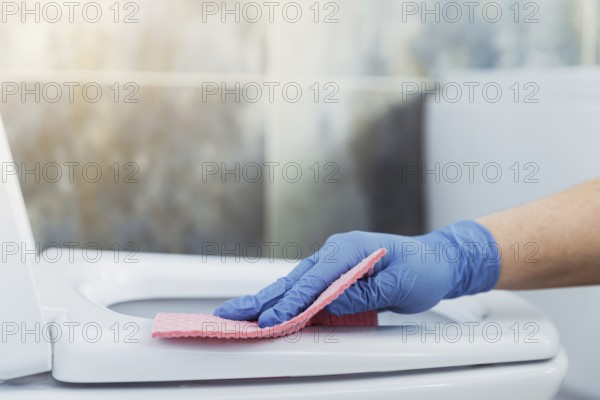 Cropped image view with close up on woman hands gloved in rubber protective gloves. Housewife
