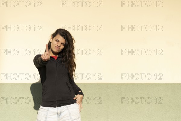 Latin teenager in a the street saying no with her hand. Stop concept. Rejection concept.