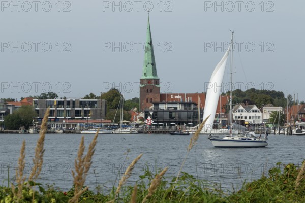 View from Priwall onto the river Trave with sailing boat and St Lorenz church, seaside resort