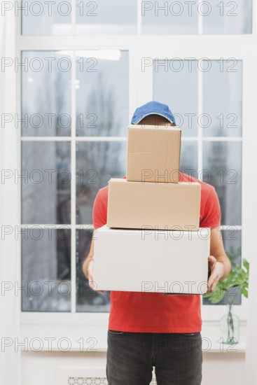 Faceless courier with stack parcels