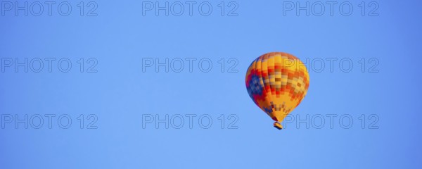 Flying hot air balloon against bright blue sky