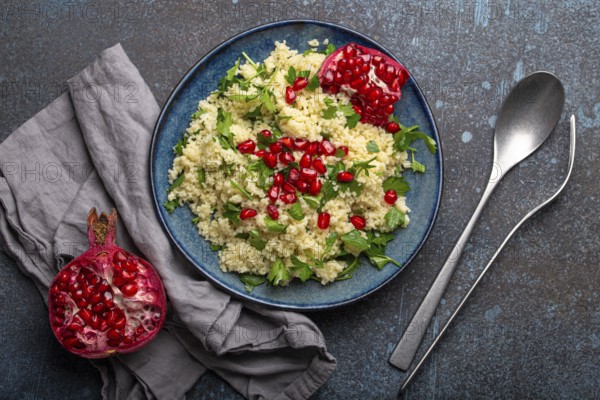 Bright colourful couscous or bulgur salad with pomegranate seeds Tabbouleh in rustic blue ceramic