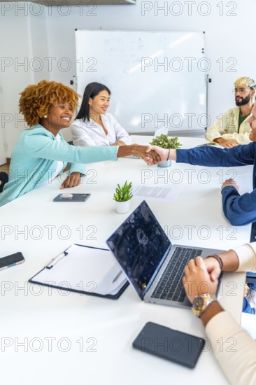 Vertical photo of multi-ethnic people greeting shaking hands on a meeting in a coworking